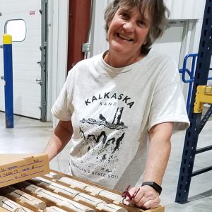 Jennifer Trout in a warehouse standing next to a box of rock core.