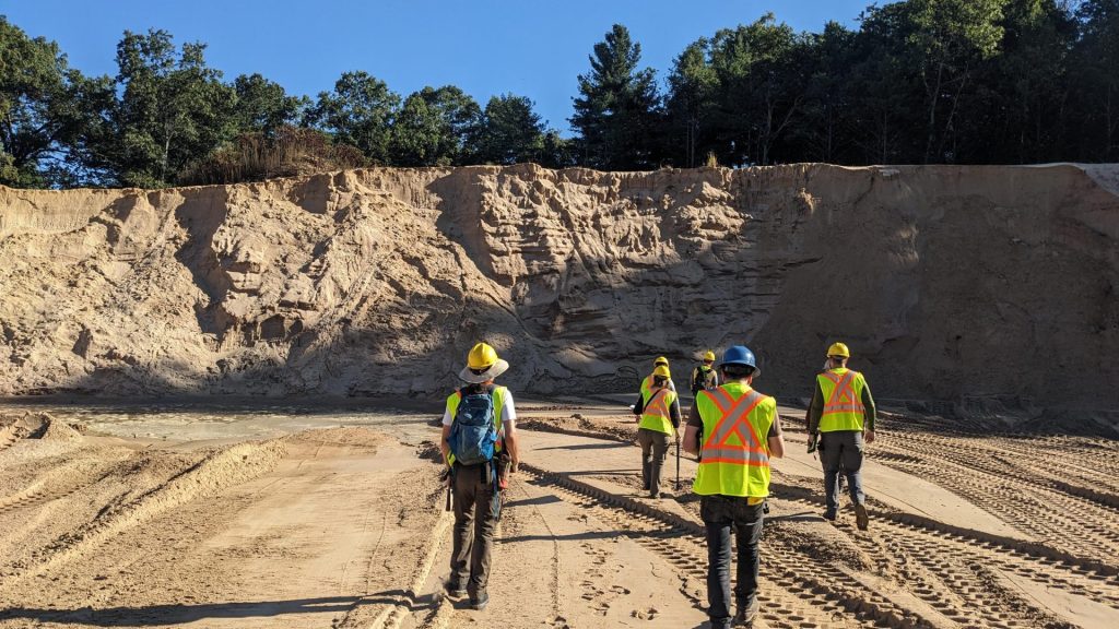 Team of geologists walking toward the edge of a sandpit