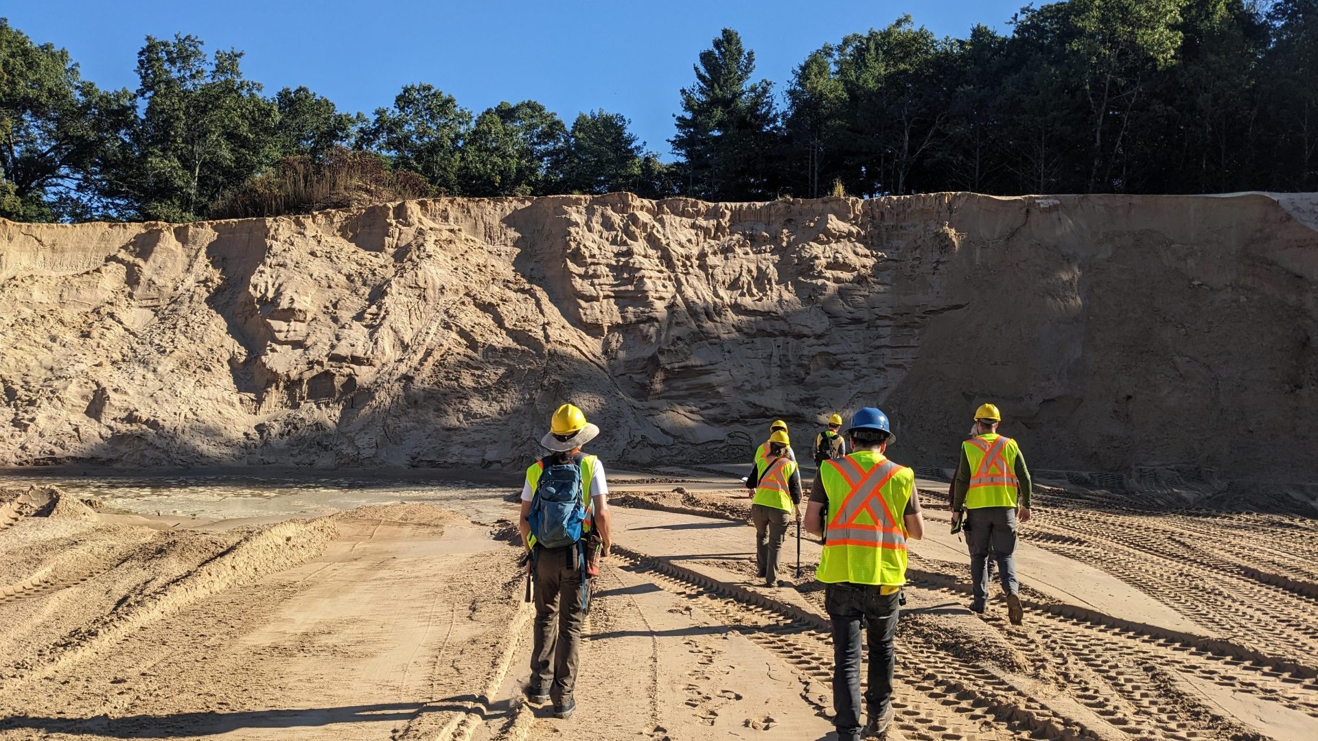 Team of geologists walking toward the edge of a sandpit