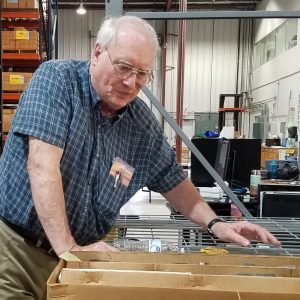Dr. Bill Harrison in a warehouse examining a cardboard box containing rock core.