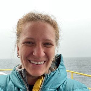 Libby Ives on a boat with gray skies and the ocean in the background.