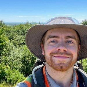 Nolan Gamet outdoors with green trees and blue sky in the background.