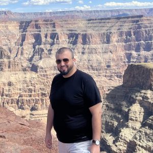 Khalid Omar standing in the foreground with rock cliffs of the Grand Canyon in the background.