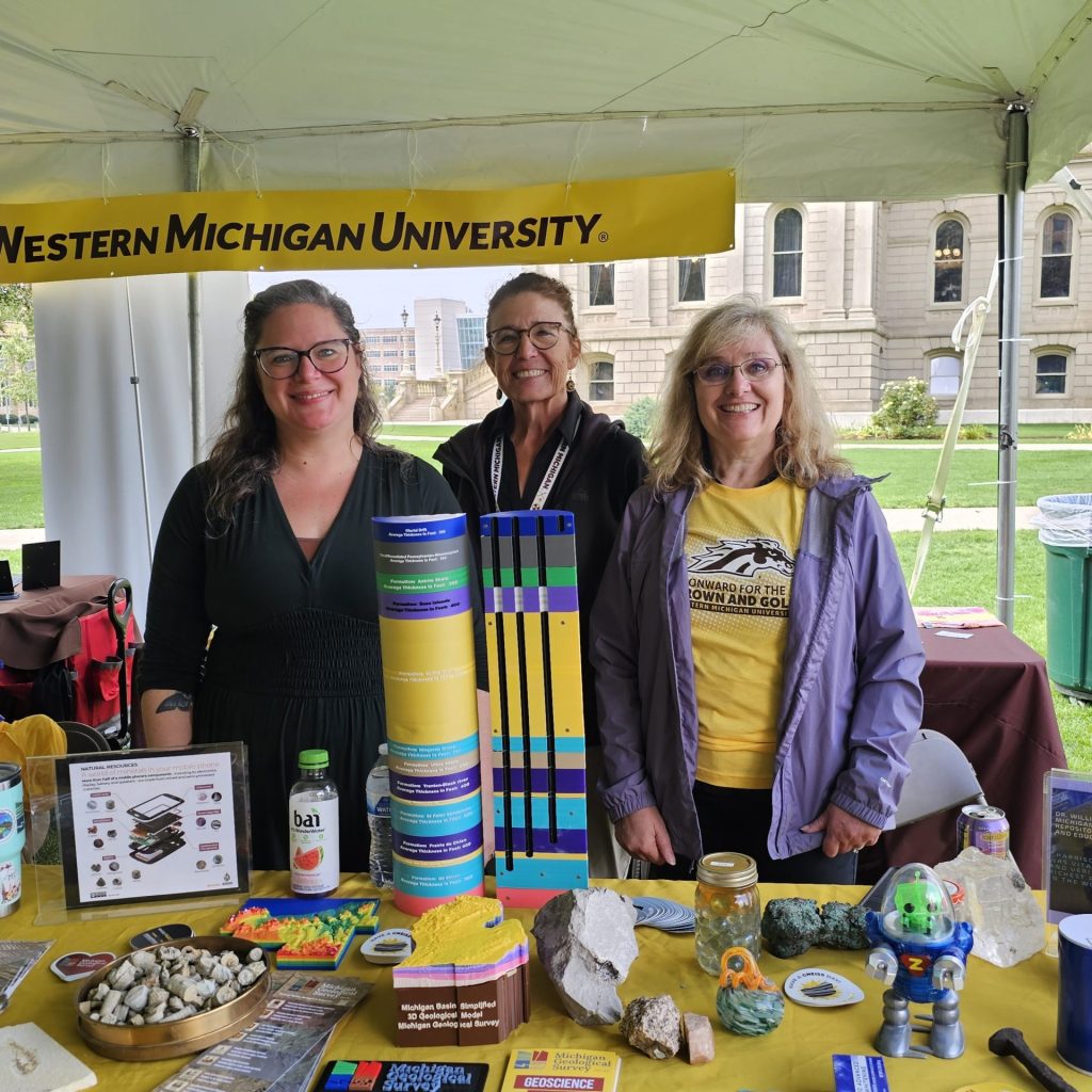 MGS staff promoting earth science education at Capitol Day in Lansing. Staff are standing behind a table covered with rocks, minerals, 3D models, and other activities.