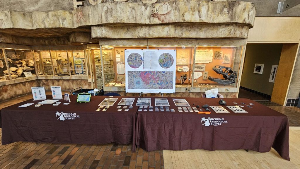 MGS outreach table with a tablecloth, handouts, rocks, a tablet, and a map.