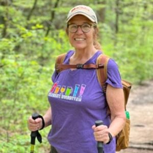 Lisa Wininger wearing a backpack while holding two hiking poles.