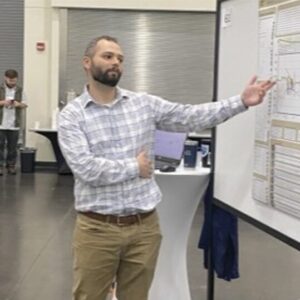 Garret Ringle pointing towards his science poster presentation.